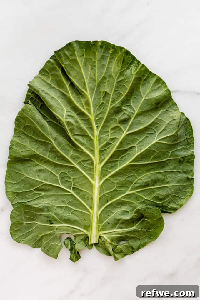 Vibrant Garden Collard Wraps 3 A large, fresh collard green leaf laid flat on a marble cutting board, ready for preparation.