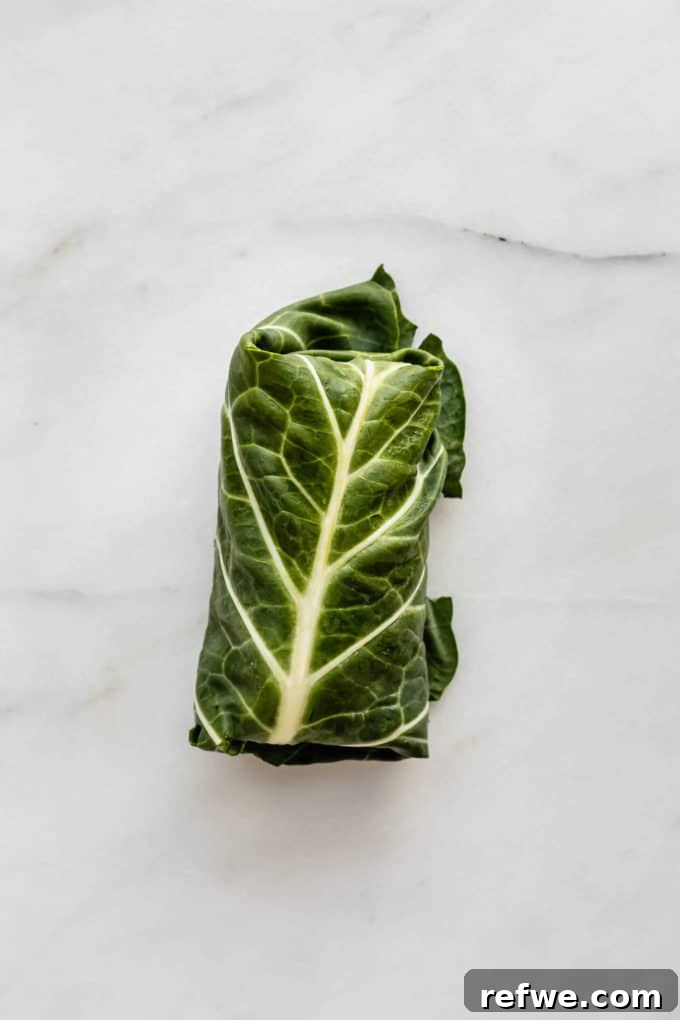 Vibrant Garden Collard Wraps 8 A freshly rolled collard green wrap, perfectly formed and ready to be sliced, resting on a marble board.