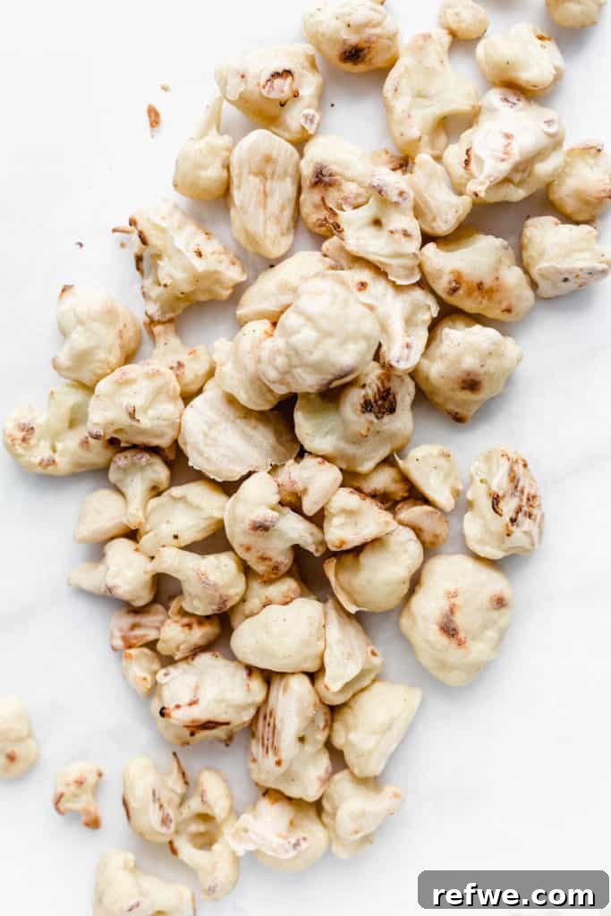 Battered and roasted cauliflower florets on a marble board, ready to be sauced