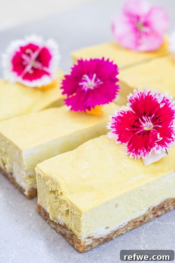 Close-up shot of creamy vegan mango cheesecake bars, showing the rich texture of the mango filling and the sturdy nut and date crust, ready to be served.