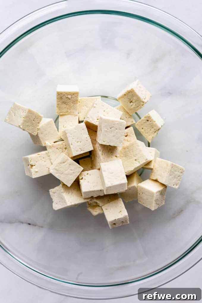 Grilled Tofu Satay with Creamy Peanut Sauce 3 Firm tofu being expertly cut into large, uniform cubes, ready for marination.
