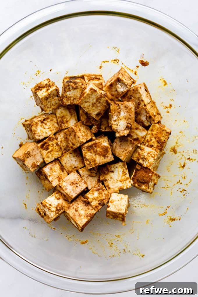 Grilled Tofu Satay with Creamy Peanut Sauce 4 A bowl filled with cubed tofu generously coated in a rich, golden satay marinade, ready for infusing flavors.