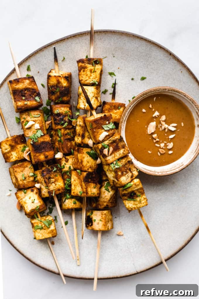 Grilled Tofu Satay with Creamy Peanut Sauce 6 A beautifully plated serving of grilled tofu satay skewers, accompanied by a small bowl of savory peanut sauce, ready to be enjoyed.