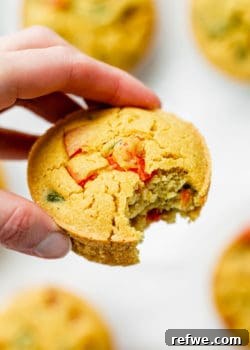 A hand holding a chickpea mini quiche, showcasing its texture and presentation.