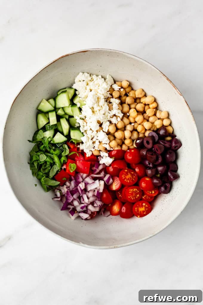 Vibrant Mediterranean Chickpea Salad 3 A colorful array of chickpeas, feta, olives, cherry tomatoes, cucumbers, and red peppers in a mixing bowl, ready for the dressing.