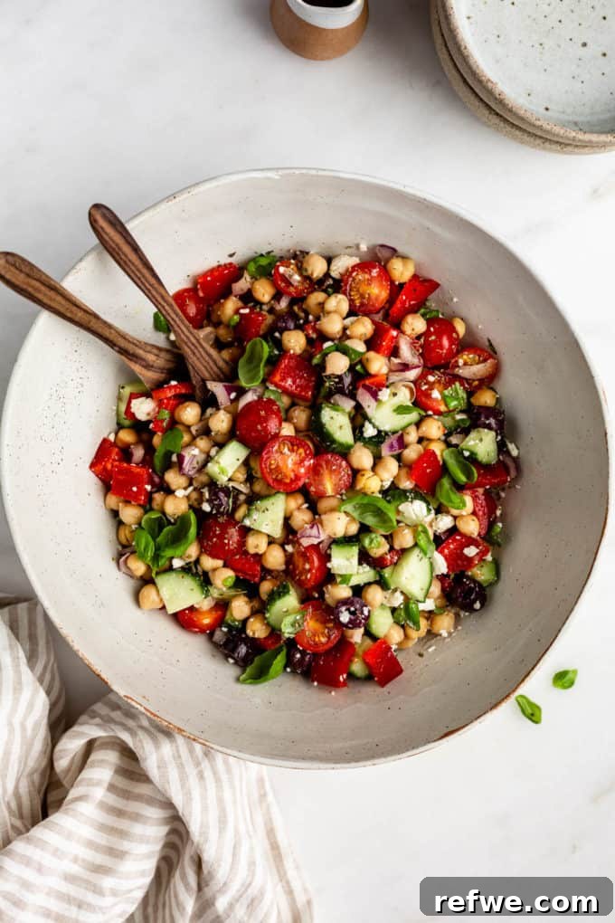 Vibrant Mediterranean Chickpea Salad 5 A beautifully presented bowl of Mediterranean Chickpea Salad, accompanied by a striped beige napkin, exuding rustic elegance.