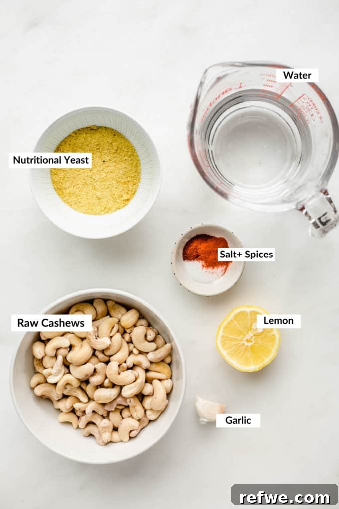 Ultimate Dairy-Free Queso 3 Raw cashews, nutritional yeast, a selection of vibrant spices, and water laid out on a stylish marble board, ready for blending into vegan queso.