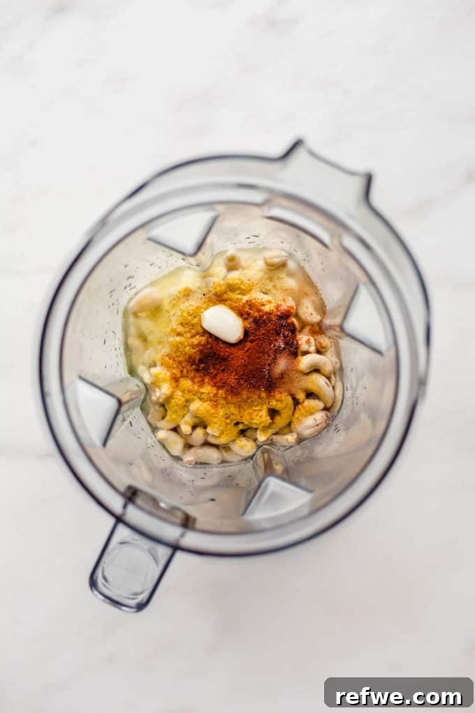 Ultimate Dairy-Free Queso 4 Raw cashews, nutritional yeast, garlic cloves, and spices are placed inside a blender jar, ready to be processed.