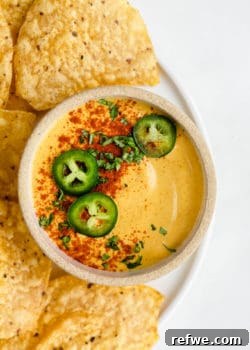 A bowl of dairy-free queso cheese topped with sliced jalapenos