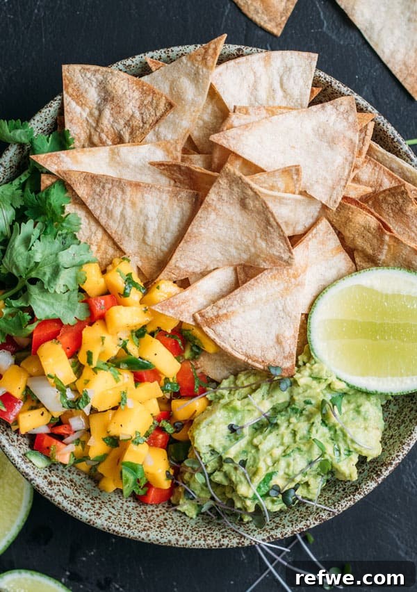 Sun-Kissed Guacamole, Mango Salsa and Crispy Baked Tortilla Chips 3 Close-up of baked corn chips arranged with bowls of guacamole and mango salsa