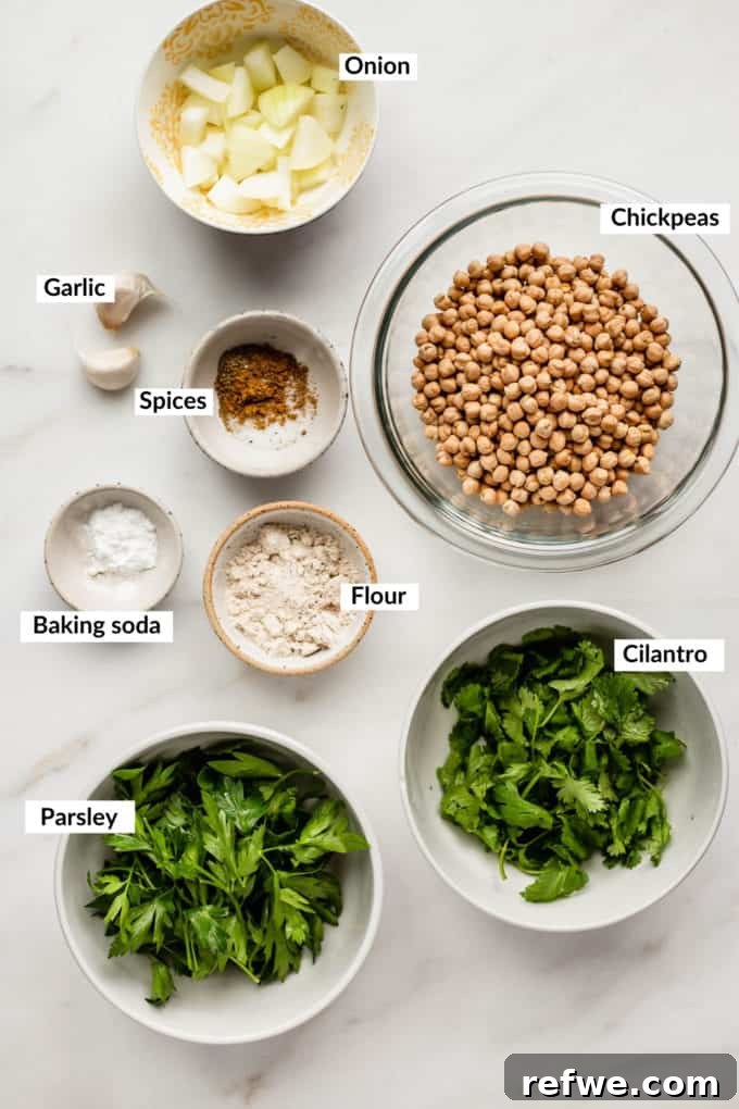 Crispy Oven-Baked Vegan Falafel 3 A vibrant arrangement of fresh herbs, dried chickpeas, various spices, chopped onions, flour, baking soda, and garlic cloves laid out on a elegant marble board