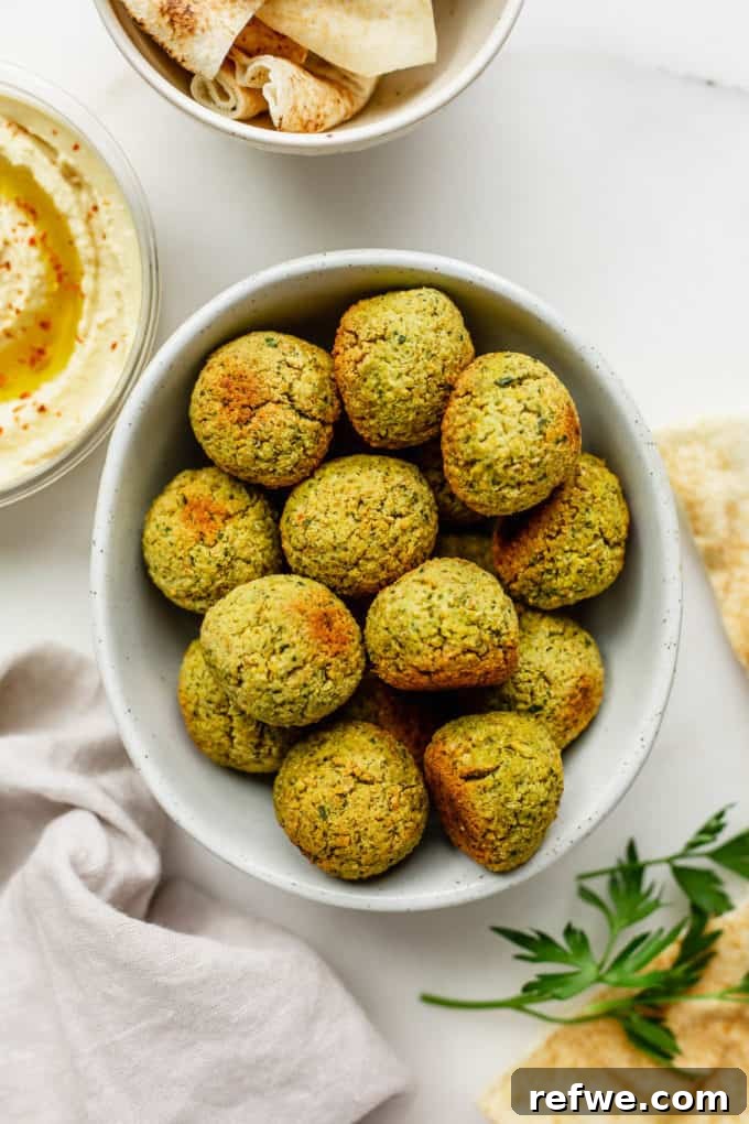 Crispy Oven-Baked Vegan Falafel 8 A beautifully presented bowl of crispy baked falafel, accompanied by warm pita bread and a creamy serving of hummus on the side