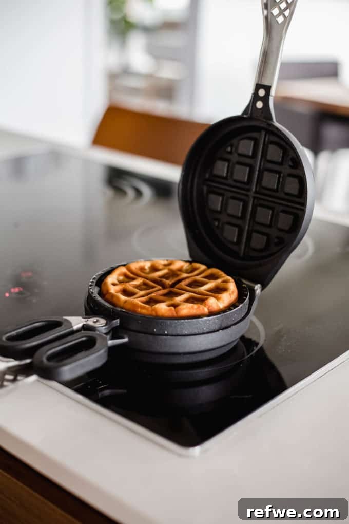 Snickers Banana Bliss Waffles 8 The Wonderffle waffle iron opened, revealing a perfectly golden-brown, cooked stuffed waffle ready to be removed.
