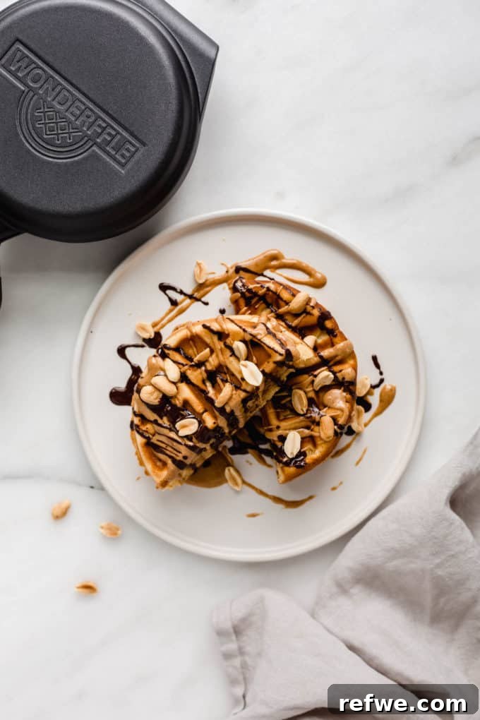 Snickers Banana Bliss Waffles 9 A whole Banana Snickers Stuffed Waffle presented beautifully on a plate next to a patterned napkin, ready to be enjoyed.