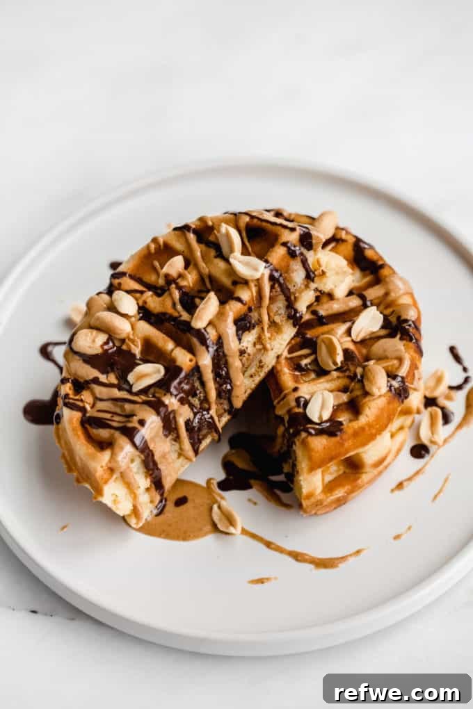 Snickers Banana Bliss Waffles 10 A Banana Snickers Stuffed Waffle, cut in half and stacked, showcasing the gooey melted peanut butter and chocolate, garnished with a few peanuts.