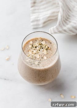 A banana bread smoothie in a glass on a marble counter
