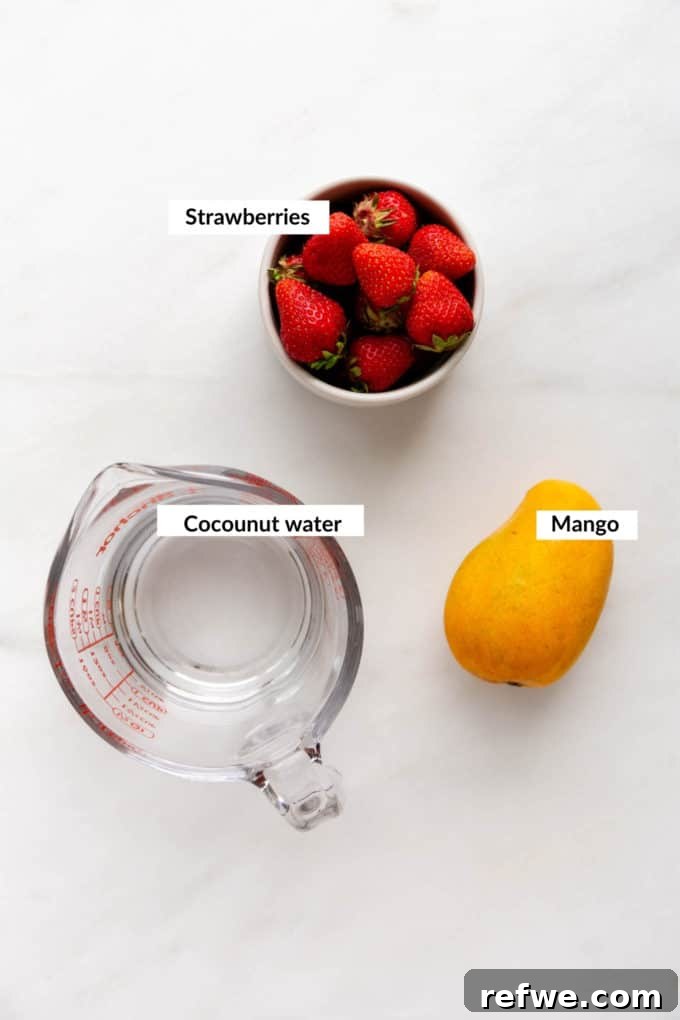 Tropical Strawberry Mango Delight 3 A fresh mango, a bowl of bright red strawberries, and a measuring cup arranged on a sleek marble table, showcasing the core ingredients for the smoothie.