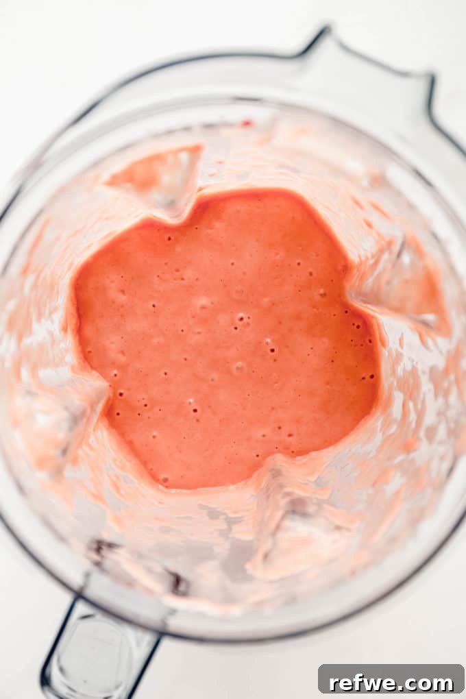 Tropical Strawberry Mango Delight 5 A close-up view inside a blender container, showing the perfectly smooth and creamy texture of the strawberry mango smoothie.