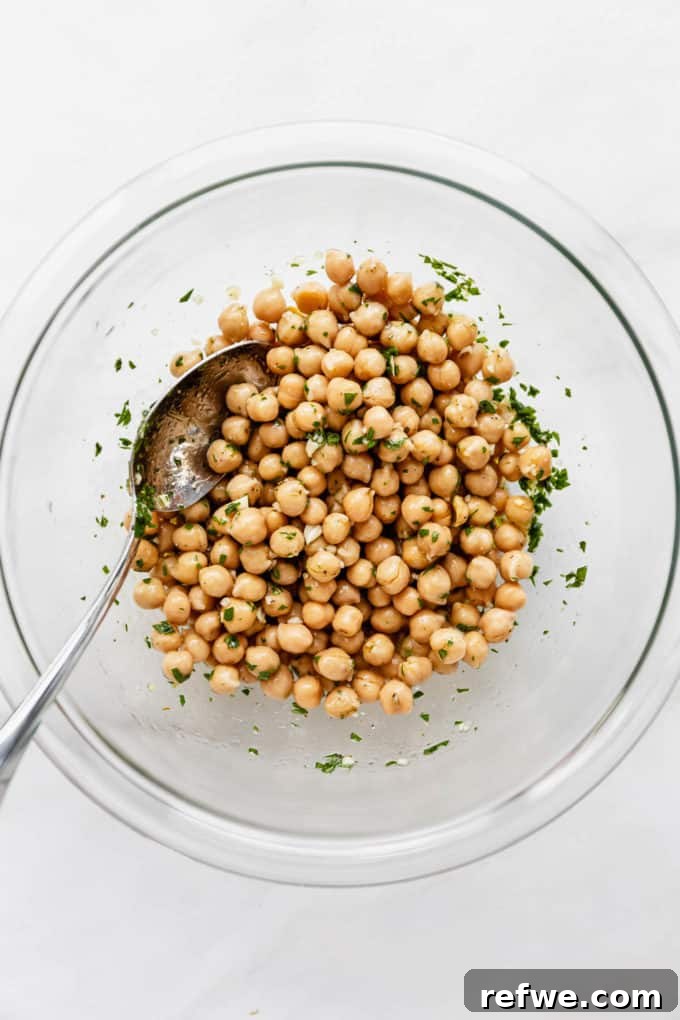 Mediterranean Vitality Bowls 5 A clear mixing bowl filled with chickpeas generously coated in a vibrant, herb-infused marinade, ready to soak up the delicious flavors.