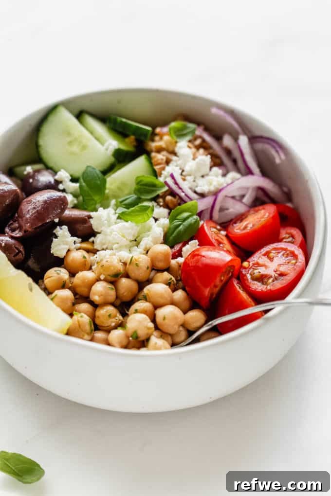 Mediterranean Vitality Bowls 7 A fully assembled Greek Power Bowl in a white ceramic bowl, showcasing marinated chickpeas, crisp vegetables, and crumbled feta cheese, ready to be enjoyed.