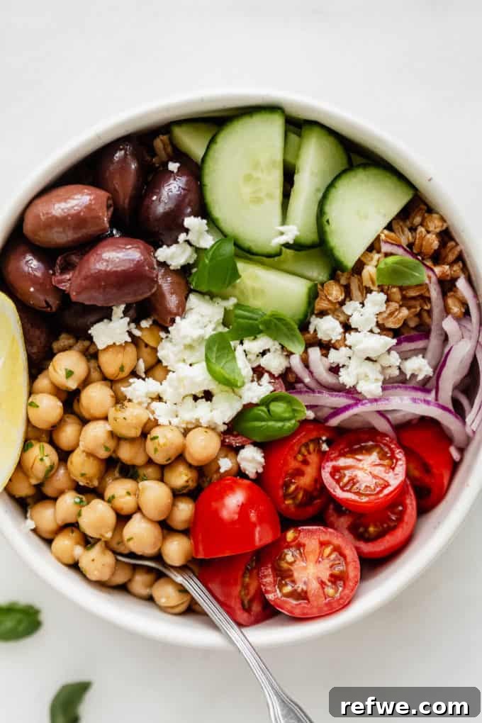 Mediterranean Vitality Bowls 8 Close-up of a Vegetarian Greek Power Bowl, highlighting the texture of chickpeas, the vibrant colors of fresh vegetables, and the crumbled feta in a white bowl.