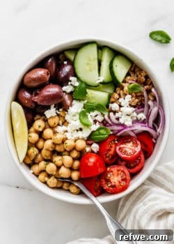 A Greek Power Bowl with chickpeas, cherry tomatoes, olives, and cucumber in a white bowl, highlighted as the main recipe image.