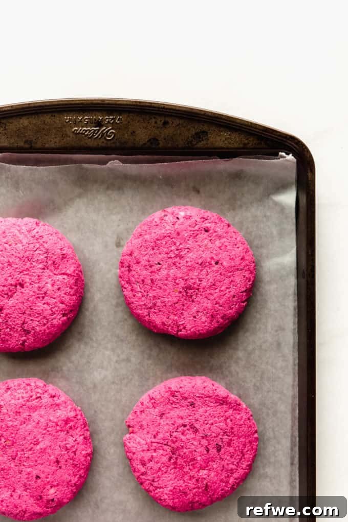 Vibrant Vegan Beet Burgers 5 Multiple raw vegan beet burger patties neatly arranged on a baking sheet lined with parchment paper, ready for baking.