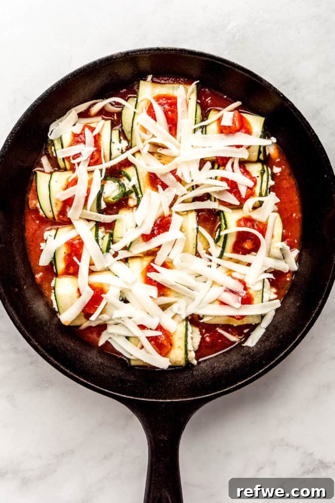 Creamy Ricotta Zucchini Pinwheels 10 Zucchini roll ups topped with shredded cheese in a cast iron skillet
