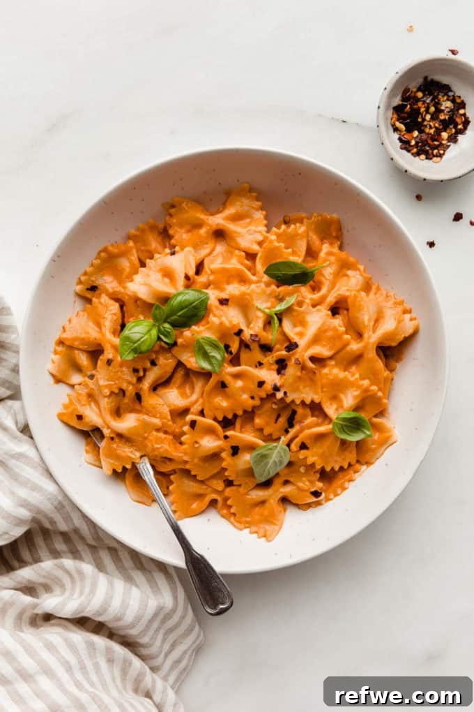 Velvety Vegan Vodka Pasta 12 A close-up shot of a bowl of vegan vodka pasta elegantly topped with fresh basil leaves, ready for enjoyment.
