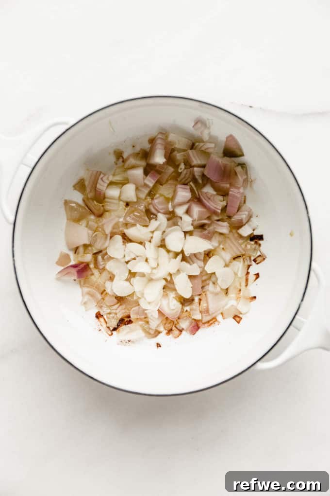 Velvety Vegan Vodka Pasta 4 A white pot containing sautéed shallots and garlic in olive oil, ready for the next step.