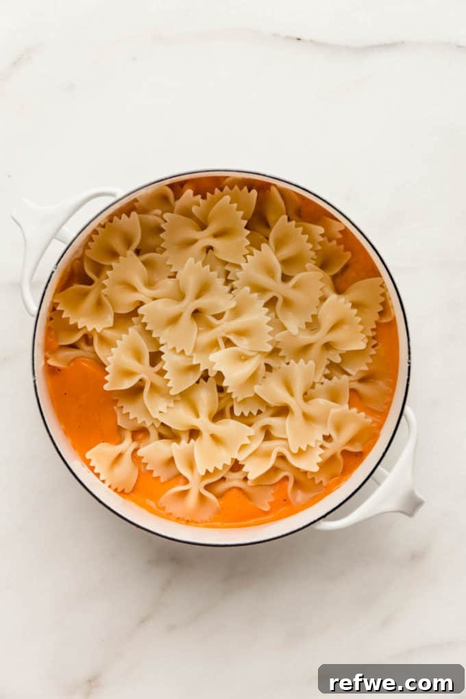 Velvety Vegan Vodka Pasta 10 A white pot containing creamy vegan vodka sauce perfectly coating farfalle pasta, stirred together for serving.