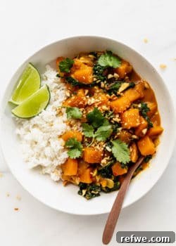 A bowl of butternut squash curry topped with cilantro and a lime wedge