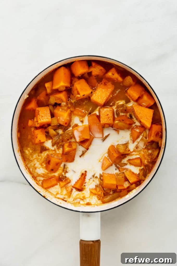 Velvet Squash Curry 7 A white pot with butternut squash, broth, and coconut milk simmering