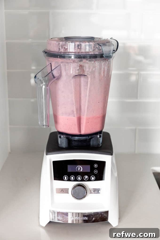 Nutrient-Rich Strawberry Banana Chia Seed Smoothie 6 A smooth, blended strawberry chia seed smoothie swirling inside a Vitamix blender, indicating it's ready to be served.