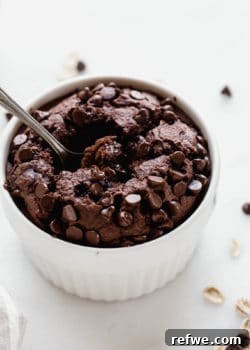 A white ramekin with chocolate baked oats in it topped with chocolate chips, ready to be served.