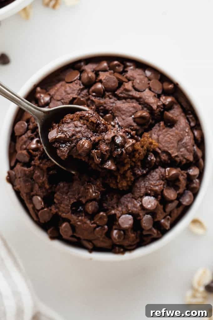 Morning Chocolate Indulgence 9 A spoon scooping up a warm, fluffy bite of chocolate baked oats from a ramekin, showing the rich texture.
