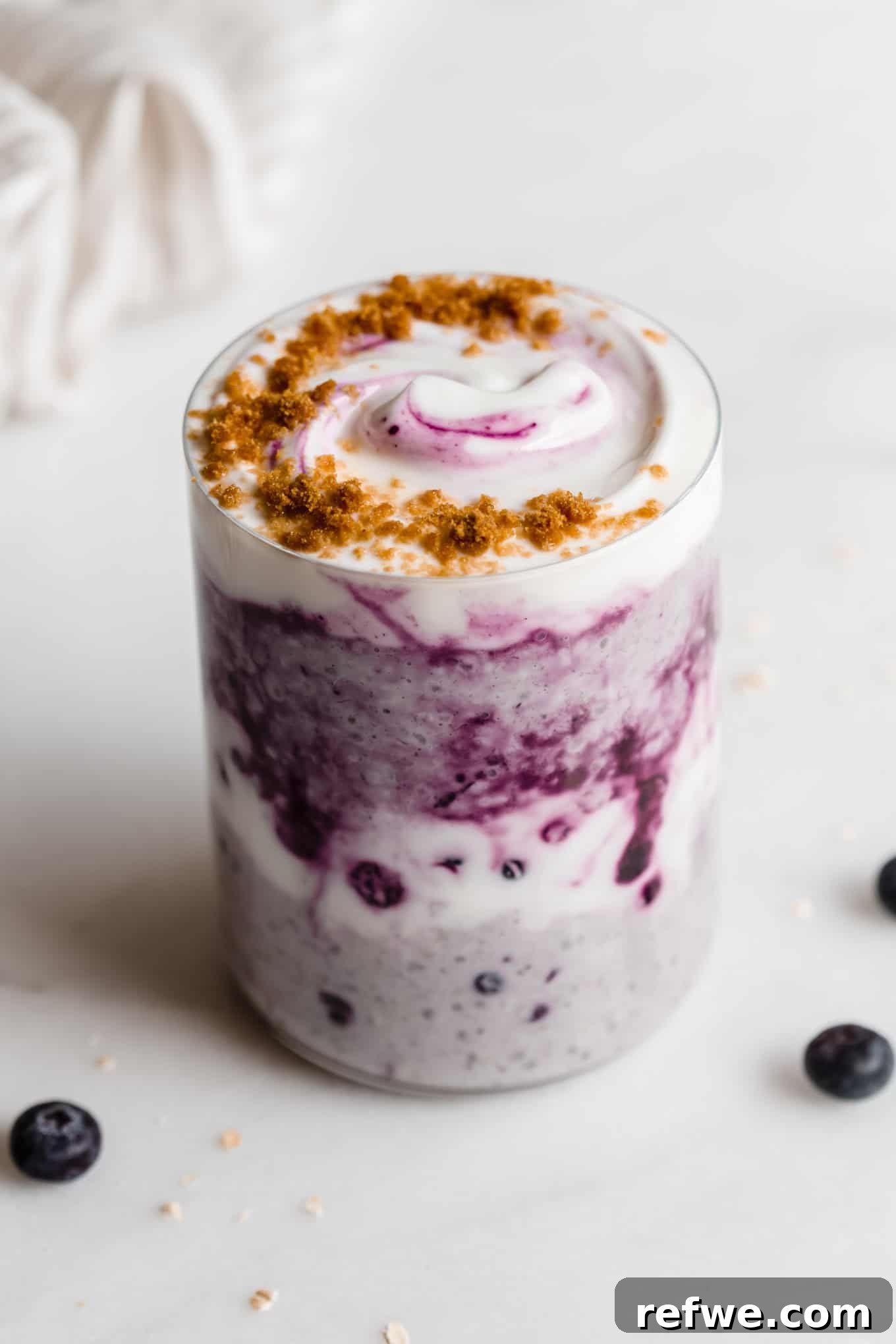 Creamy Blueberry Overnight Oats 2 A cup of blueberry overnight oats topped with fresh blueberries, a dollop of yogurt, and crunchy graham crackers.