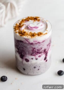 A cup of blueberry overnight oats topped with yogurt and crushed graham crackers.