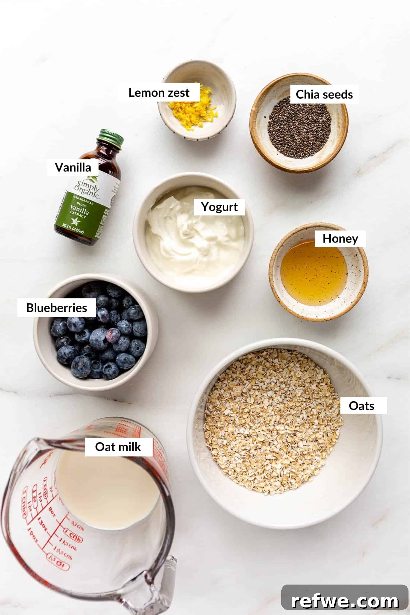 Creamy Blueberry Overnight Oats 3 A flat lay of fresh blueberries, rolled oats, chia seeds, milk, yogurt, and honey – all the ingredients to make blueberry overnight oats