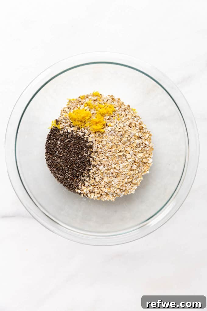 Creamy Blueberry Overnight Oats 4 A clear mixing bowl with rolled oats, chia seeds, and lemon zest, ready to be mixed.