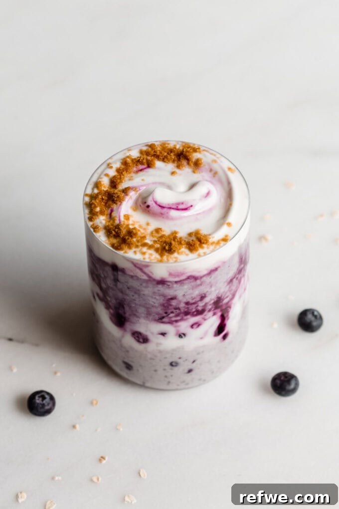 Creamy Blueberry Overnight Oats 9 A beautifully presented jar of blueberry overnight oats on a white marble counter, garnished with fresh blueberries.