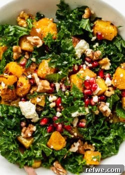 A close up of a kale and pumpkin salad topped with walnuts and pomegranate