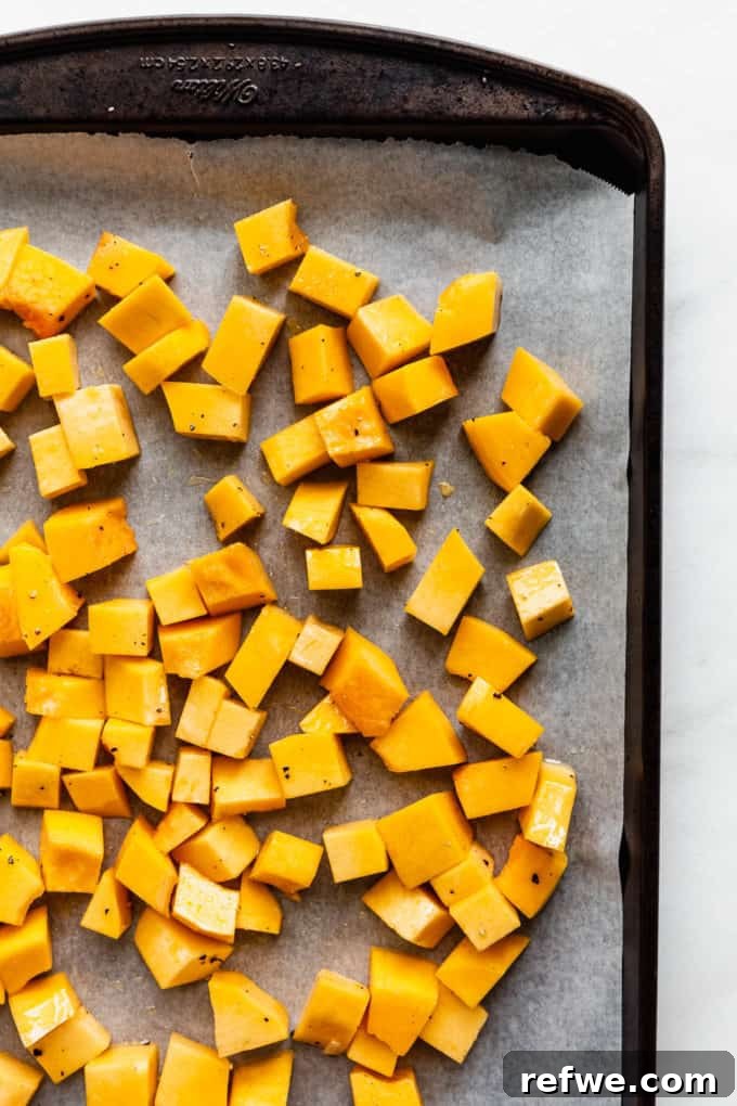 Autumn Roasted Pumpkin Salad 6 Raw pumpkin cubes arranged neatly in a single layer on a parchment-lined baking sheet, prepared for roasting.