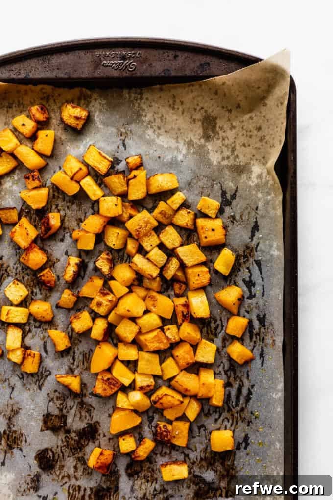 Autumn Roasted Pumpkin Salad 7 Roasted pumpkin cubes, perfectly golden and tender, spread out on a baking sheet after cooking.