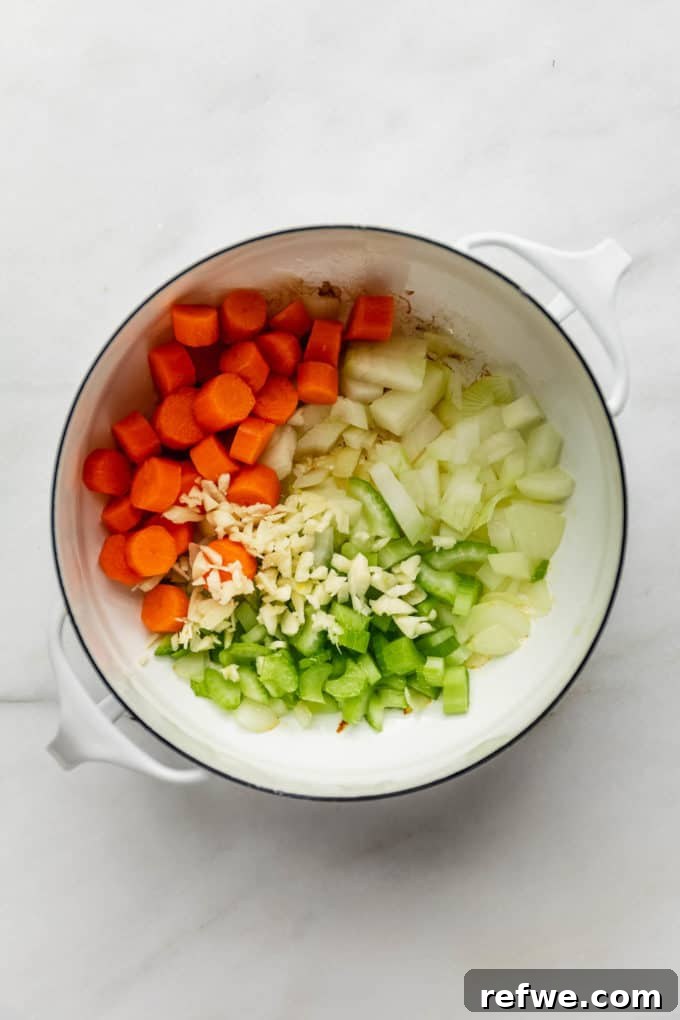 Nourishing Plant-Based Lentil Stew 4 A white pot with carrots, celery, onions and garlic sautéing