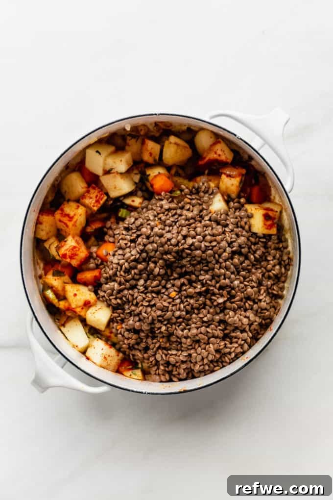 Nourishing Plant-Based Lentil Stew 6 A white pot with brown lentils and potatoes added to the vegetables