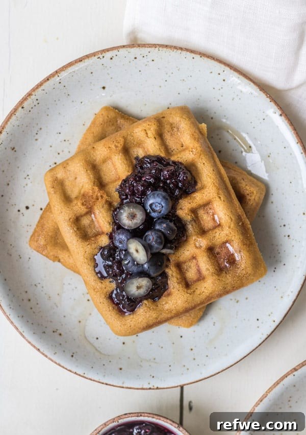 Overhead shot of cornbread waffles with blueberry compote, garnished with fresh blueberries and mint