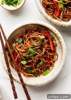 A bowl of vegan chow mein with chopsticks on top