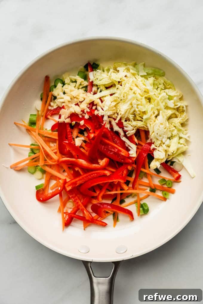 Plant-Based Vegetable Noodle Stir-Fry 4 A white pan with vibrant peppers, carrots, and cabbage beginning to soften during the sautéing process.