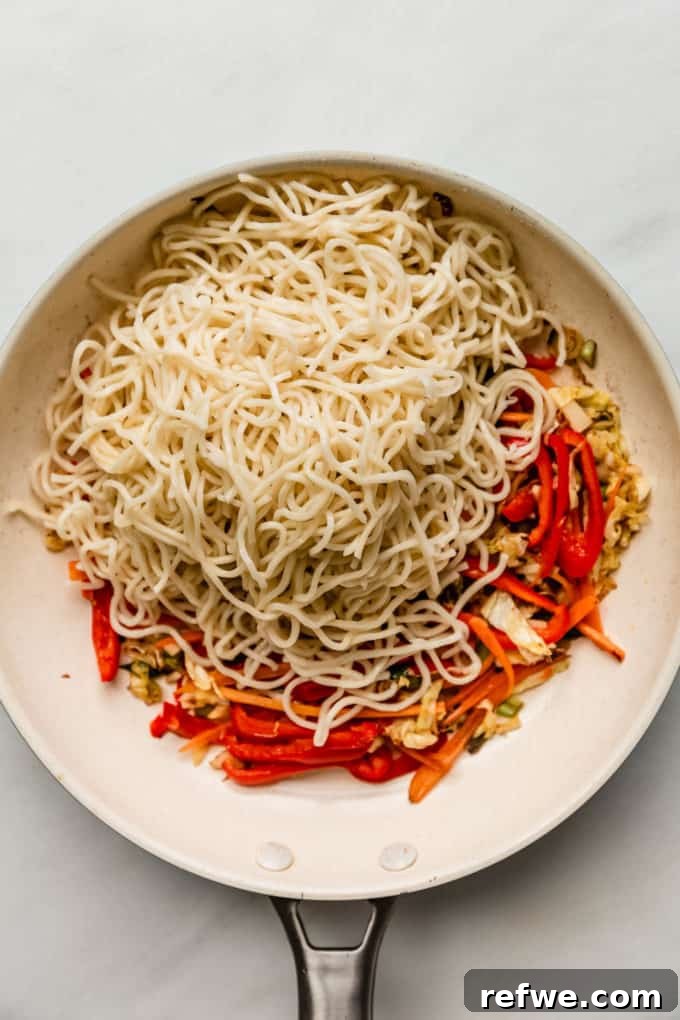 Plant-Based Vegetable Noodle Stir-Fry 6 A white pan now holds cooked noodles mixed with the stir-fried vegetables, ready for the sauce.
